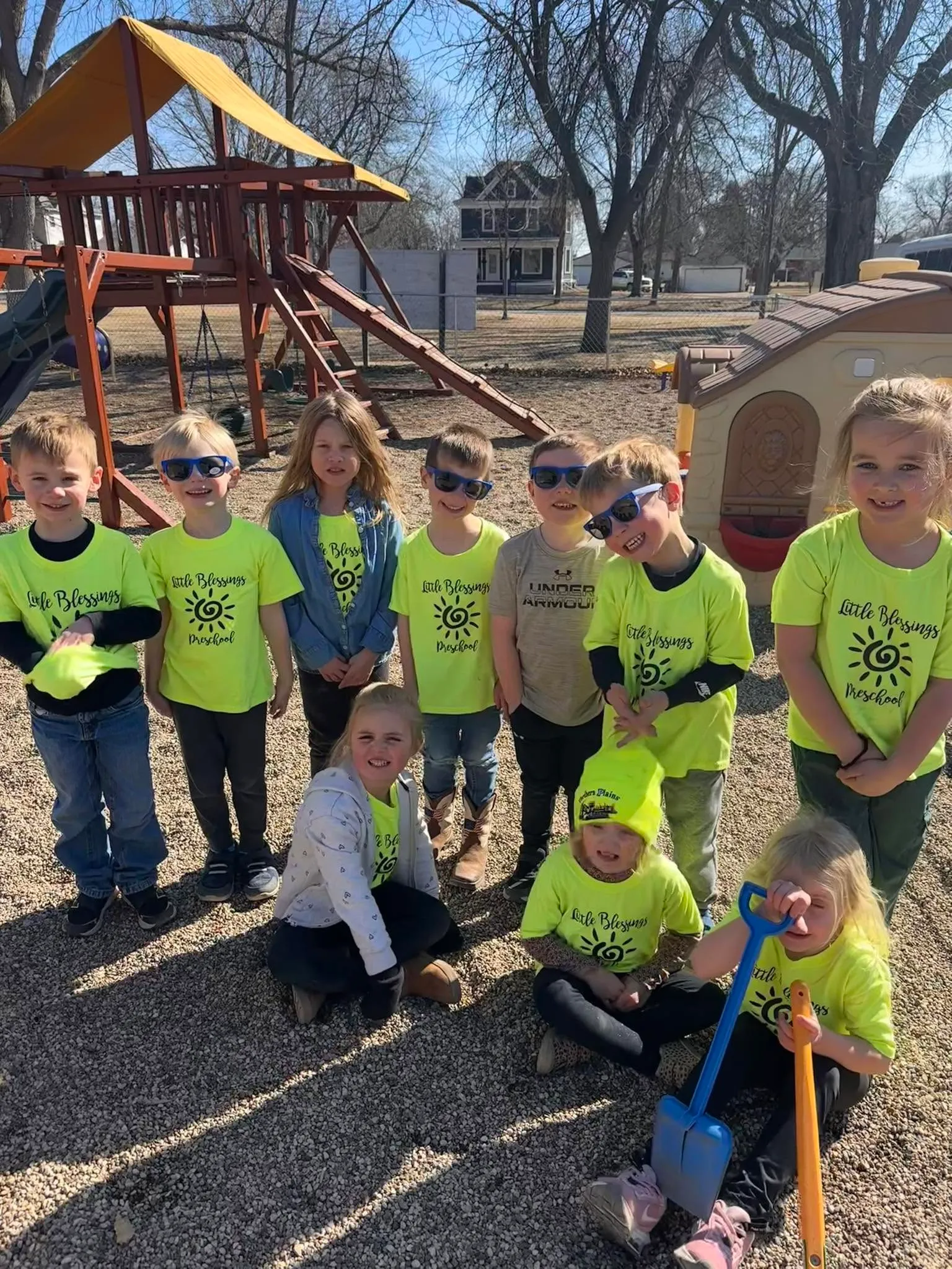 The Little Blessings Preschool class smiling together on the playground in their bright green Little Blessings shirts